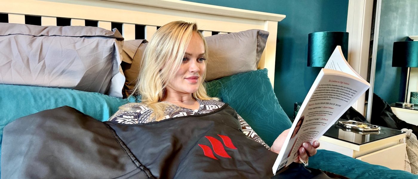 blonde woman reading a book whilst using MiHigh sauna blanket