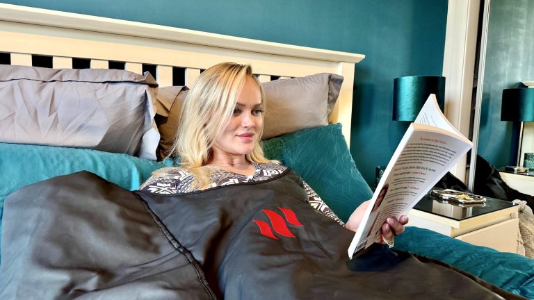 blonde woman reading a book whilst using MiHigh sauna blanket