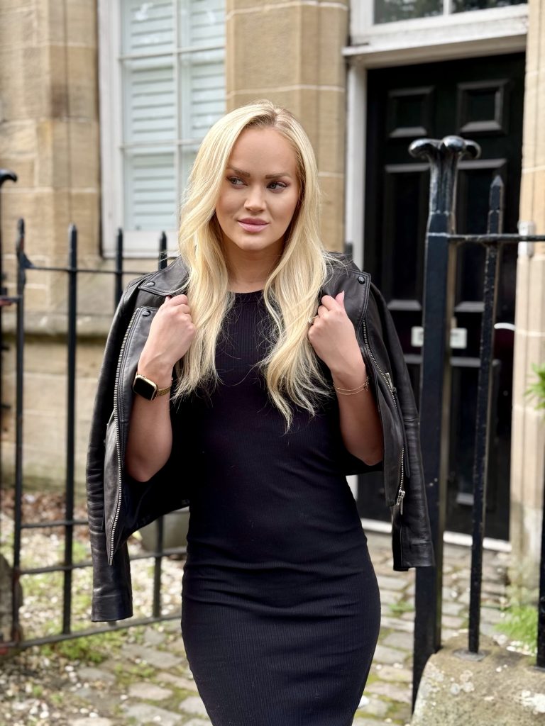 Girl drapes leather jacket over her shoulders as spring outfit
