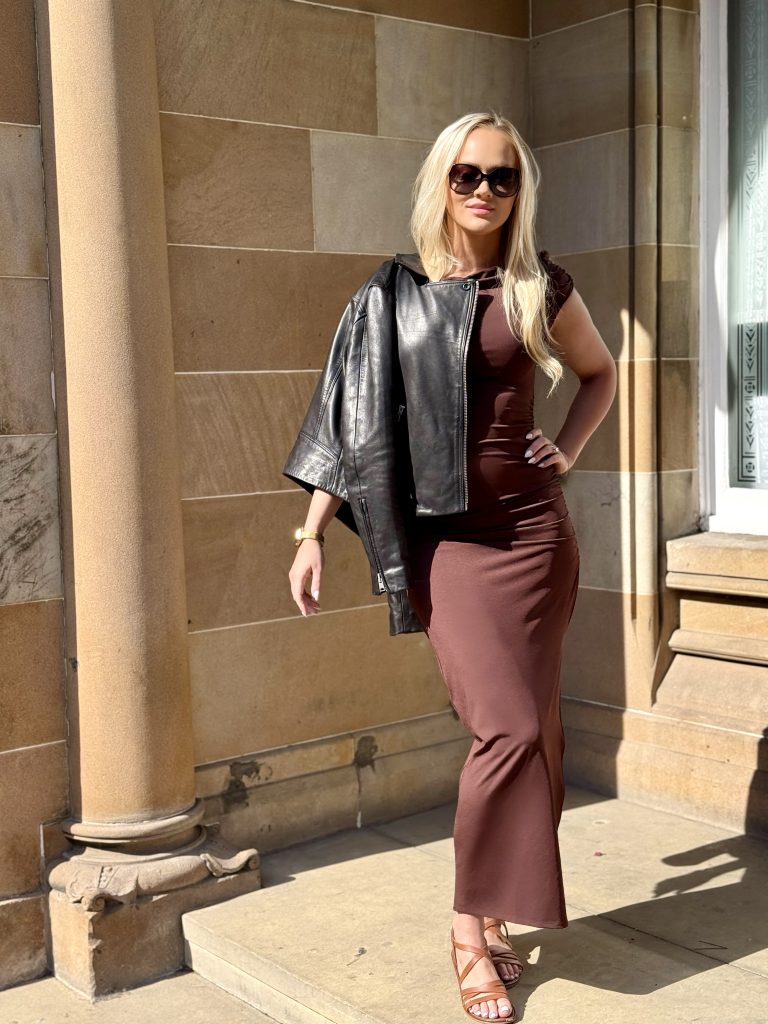 Black leather jacket draped on shoulder with brown maxi dress