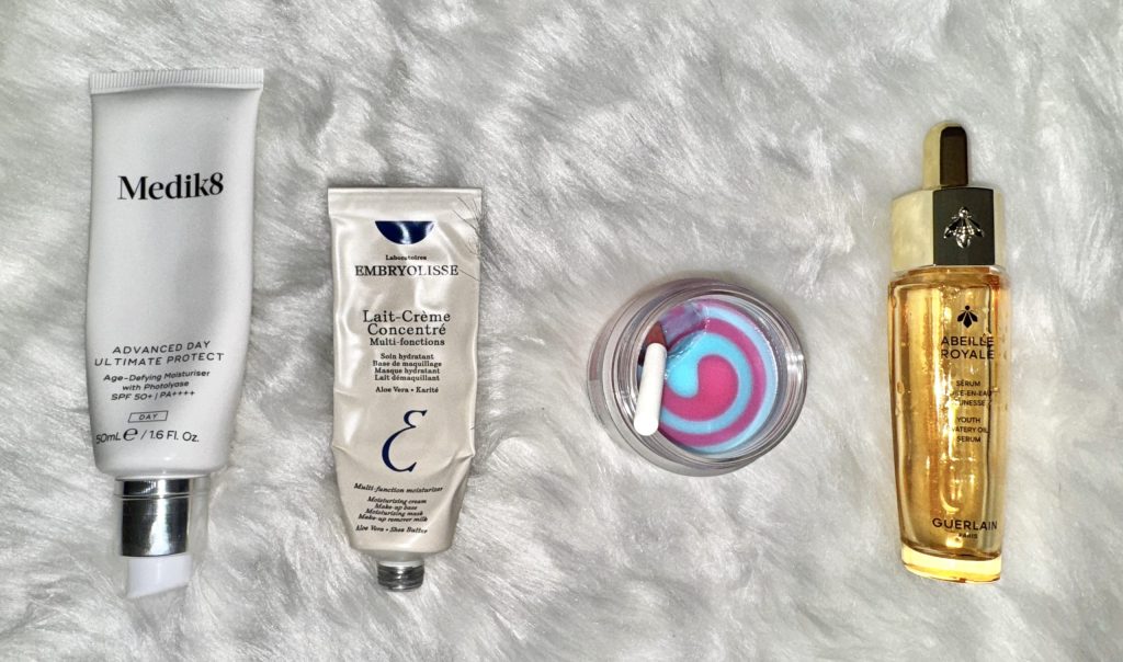 a selection of winter skincare routine products on a white fur background