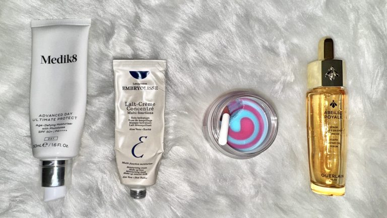 a selection of winter skincare routine products on a white fur background