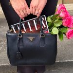 elegant fashion - simple Prada handbag held by a woman with an engagement ring