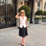 girl stands in elegant waistcoat and skirt in front of the Ritz, Paris